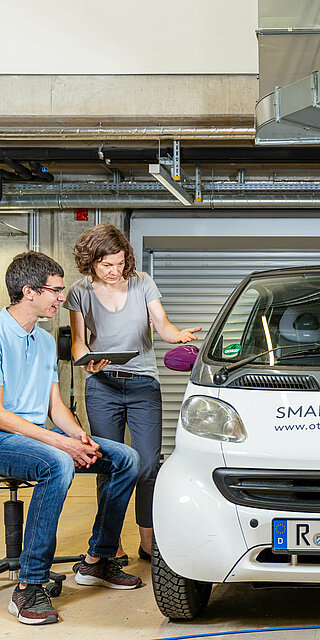 Zwei Studierende arbeiten an einem E-Auto.