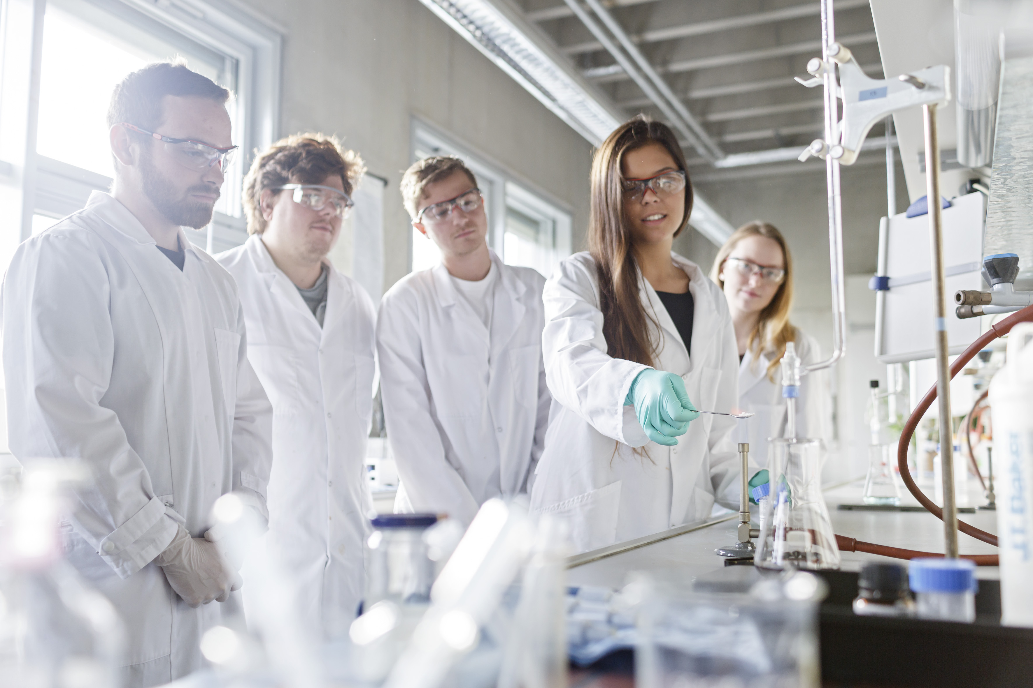 Studierende in weißen Kitteln experimentieren