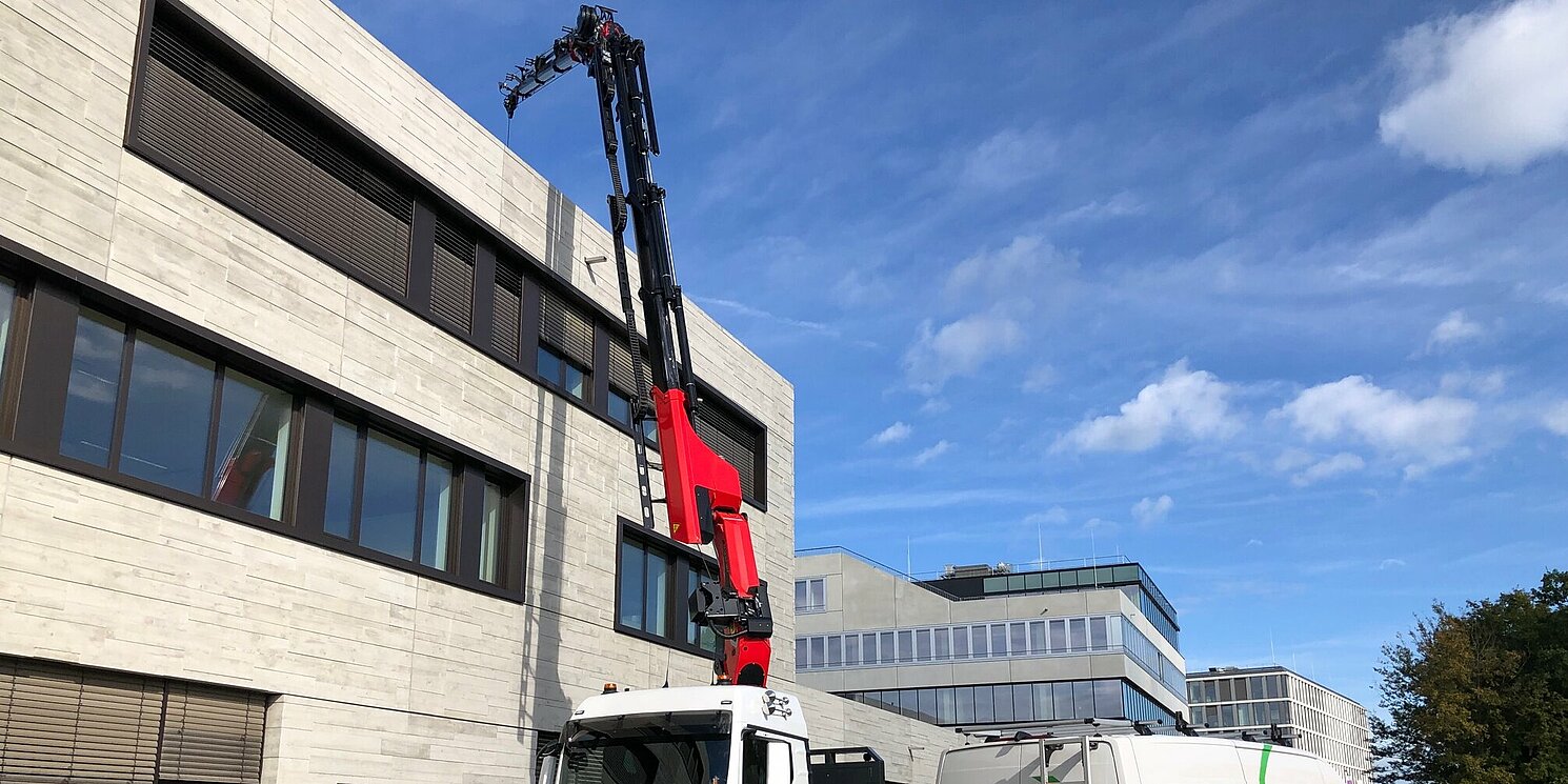 Ein Kran montiert PV-Module auf einem Gebäude.