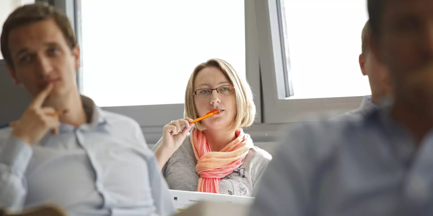 Vier Studierende sitzen in einem Seminarraum an ihren Plätzen 