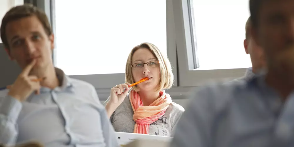 Vier Studierende sitzen in einem Seminarraum an ihren Plätzen 