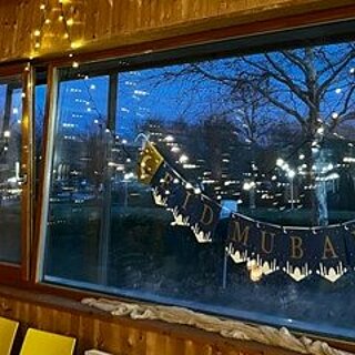 Festliche Lichter und ein „Eid Mubarak“-Banner sorgen für eine warme, einladende Atmosphäre.