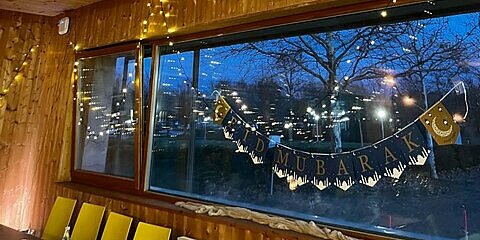 Festliche Lichter und ein „Eid Mubarak“-Banner sorgen für eine warme, einladende Atmosphäre.