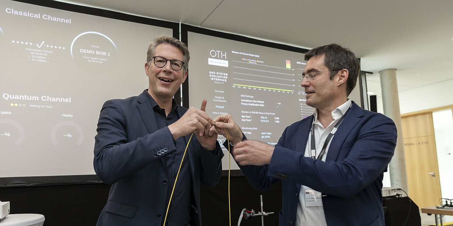 Zwei Männer verbinden ein Kabel über eine Steckverbindung.