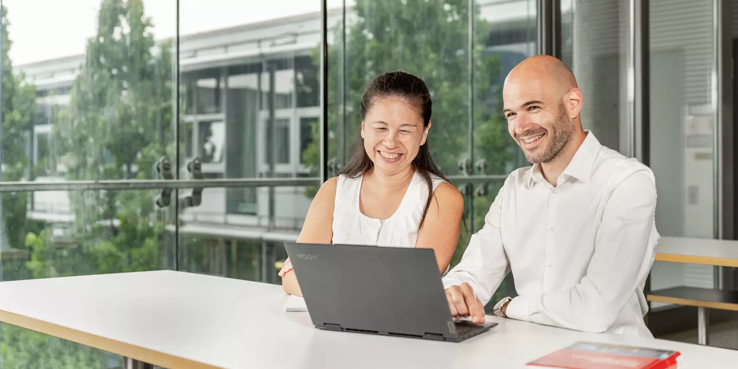 Module aus dem Master Business Administration – General Management berufsbegleitend absolvieren Zwei Studierende lernen gemeinsam an einem Tisch mit einem Laptop.