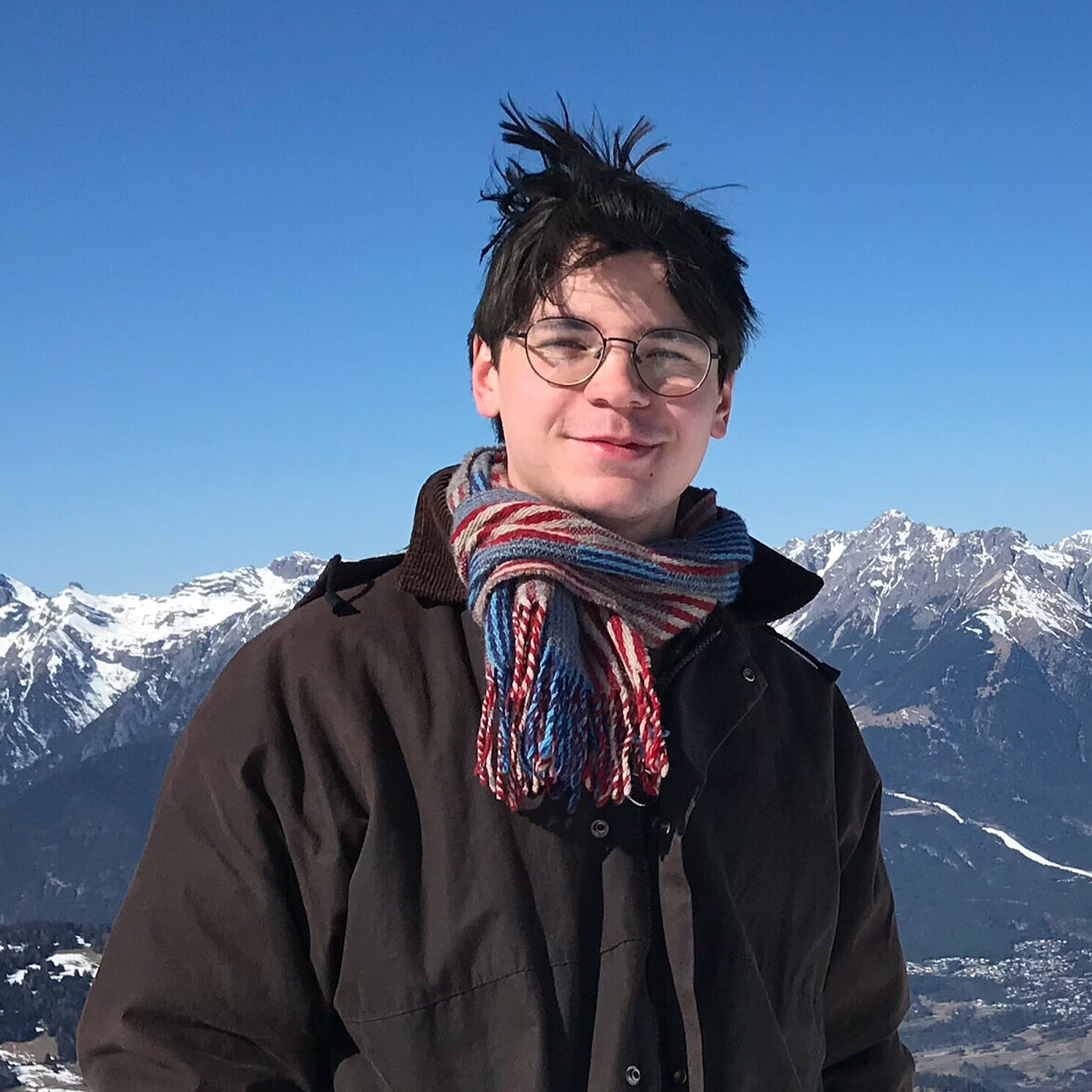 Auf dem Foto ist eine Person frontal zu sehen. Sie steht vor einem grünen Hintergrund.