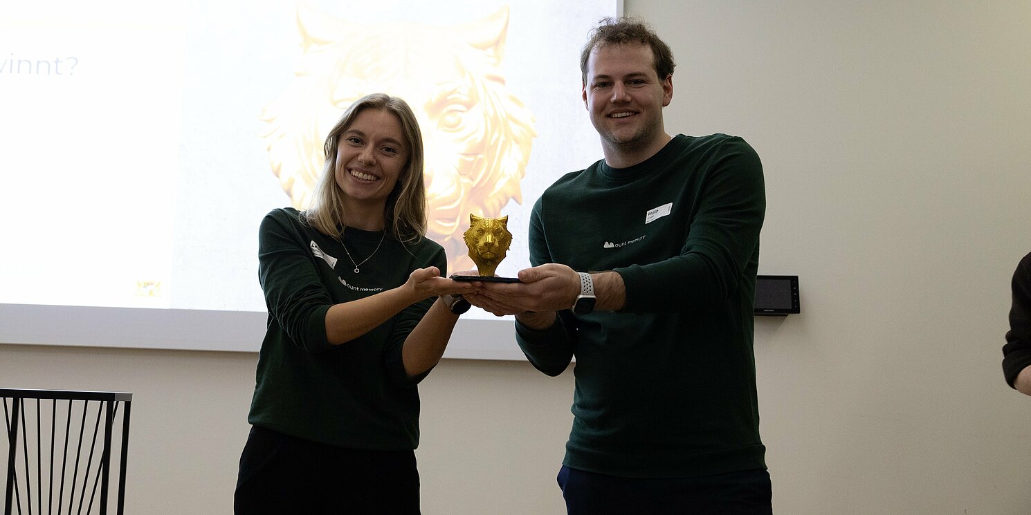 Eine Frau und ein Mann heben gemeinsam die Siegertrophäe