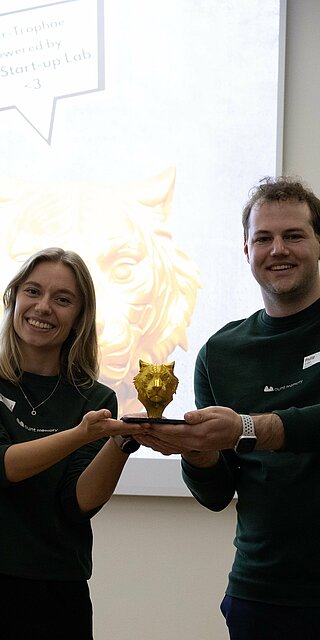 Eine Frau und ein Mann heben gemeinsam die Siegertrophäe