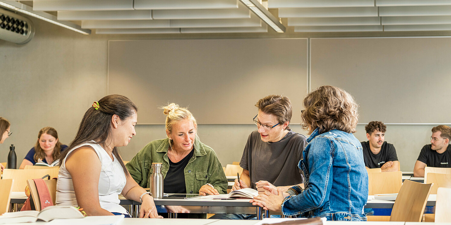 Studierende arbeiten in Gruppen in einem Seminarraum. 