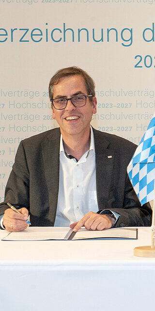 Zwei Männer sitzen an einem Tisch und unterschreiben ein Dokument.