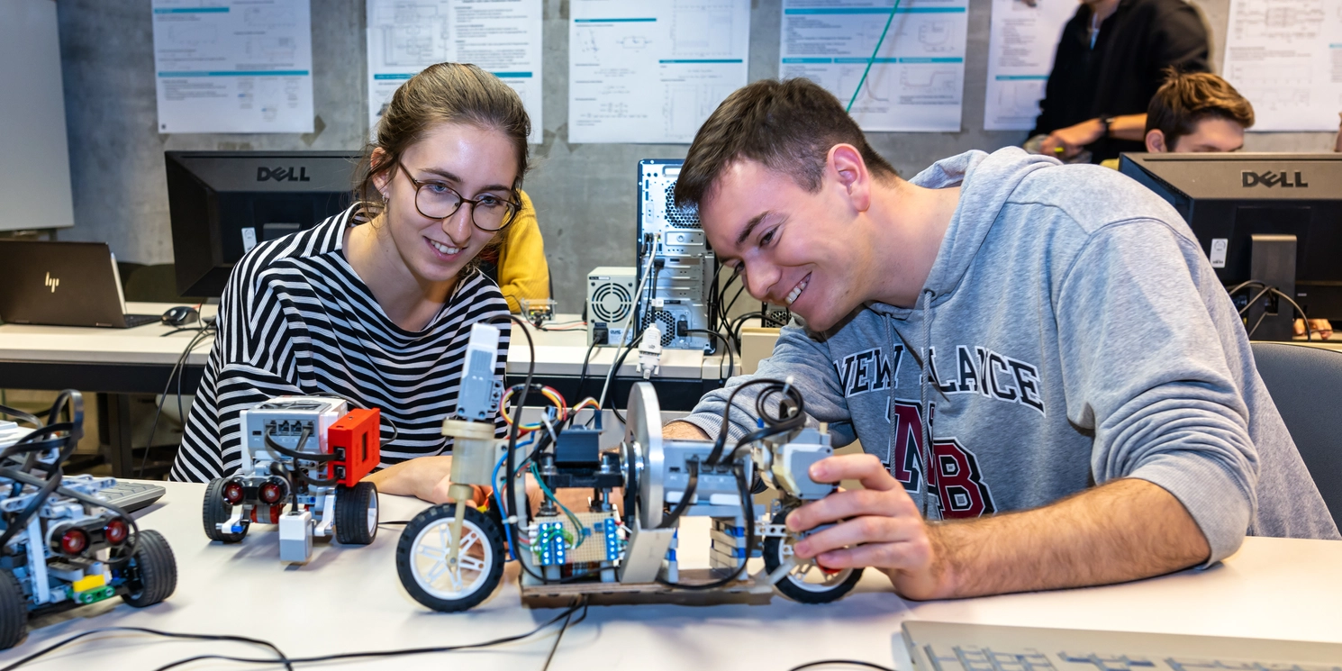 Zwei Studierende im Labor Regelungstechnik bei der Arbeit an einem kleinen Fahrzeug