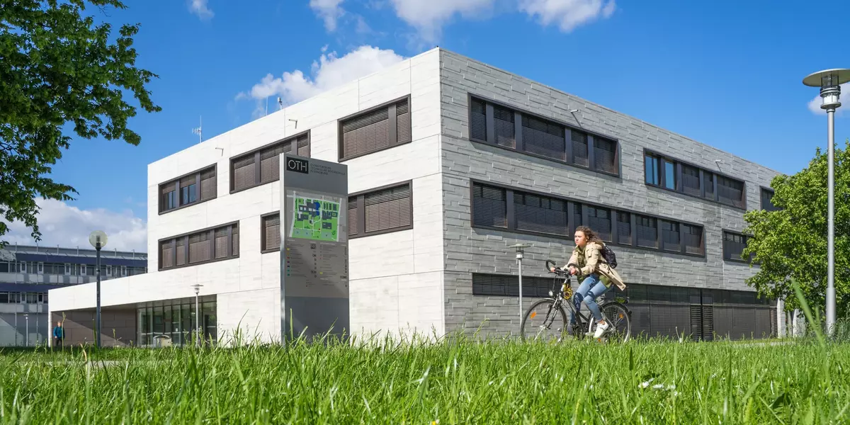 Bild des Vielberth-Gebäudes der Universität Regensburg. Davor eine Person auf dem Fahrrad.
