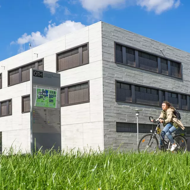 Bild des Vielberth-Gebäudes der Universität Regensburg. Davor eine Person auf dem Fahrrad.
