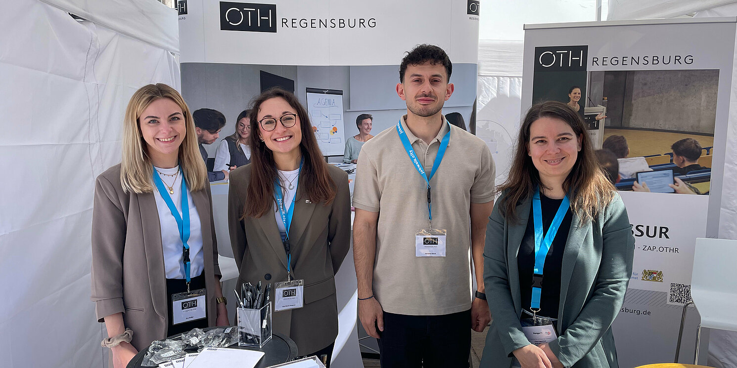 Vier Personen stehen an einem Messestand