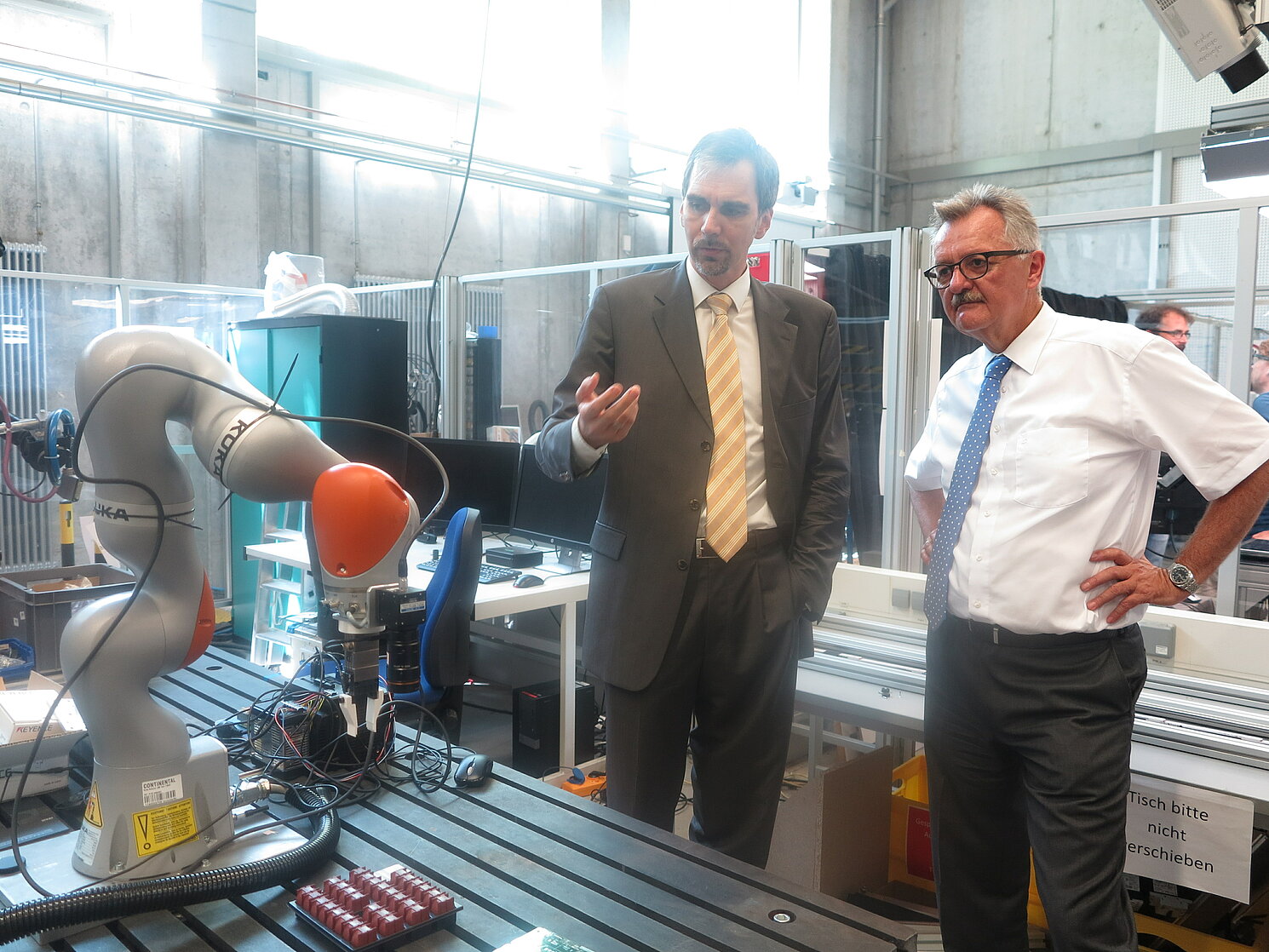 Prof. Dr. Thomas Schlegl (links) präsentiert Ministerialdirektor Dr. Müller das Labor Robotik, Fakultät Maschinenbau.