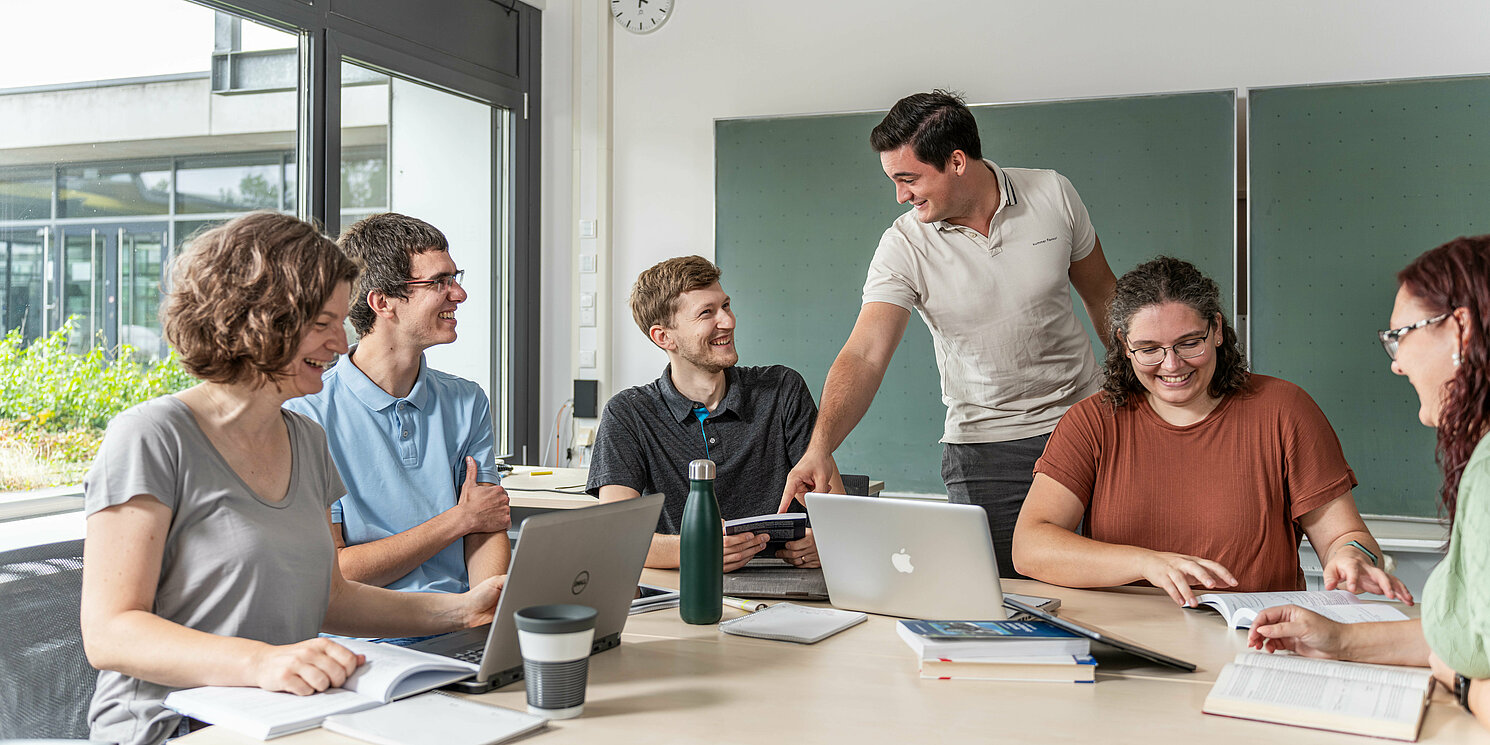 Fachseminar Consulting Skills – Problemsolving und Chartdesign berufsbegleitend absolvieren Studierende arbeiten in einer Lerngruppe mit Laptops und Unterlagen an einem großen Tisch.