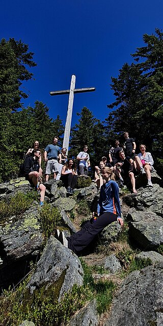 Studierende sitzen um das Gipfelkreuz am Predigtstuhl.