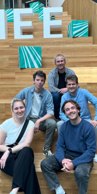 Vier Personen der OTH Regensburg sitzen auf der Treppe beim Das Team der OTH Regensburg (oben: Alexander Meisinger, mittig v.l.n.r.: Leon Schumm, Anton Achhammer, unten v.l.n.r.: Elisabeth Hockemeyer, Marco Schamel) beim diesjährigen Projektreffen im Fraunhofer IEE, Kassel. 