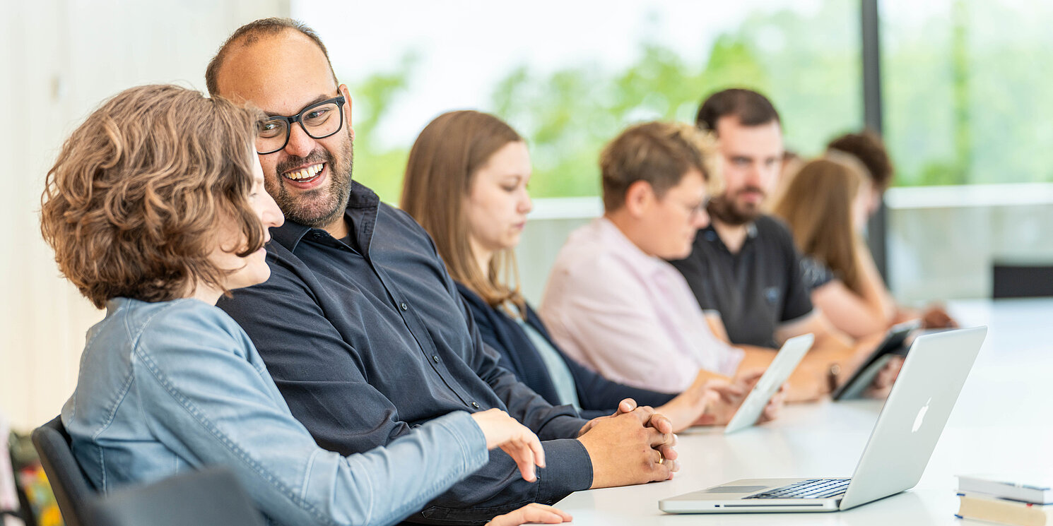 Studierende lernen und unterhalten sich in einem Seminarraum. 
