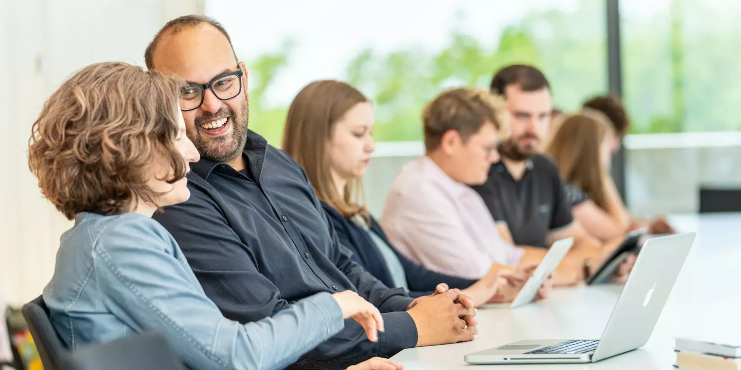 Study Management and Communications part-time Studierende lernen und unterhalten sich in einem Seminarraum.