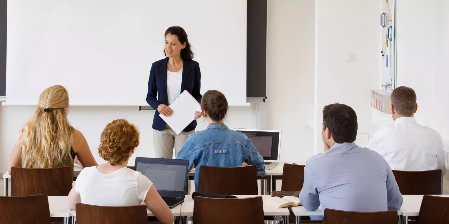 Hochschulzertifikat Betriebliches Gesundheitsmanagement berufsbegleitend absolvieren Dozentin mit fünf Studierenden in einem Seminarraum