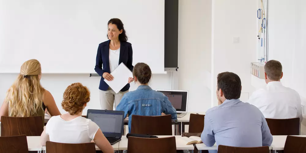 Dozentin mit fünf Studierenden in einem Seminarraum