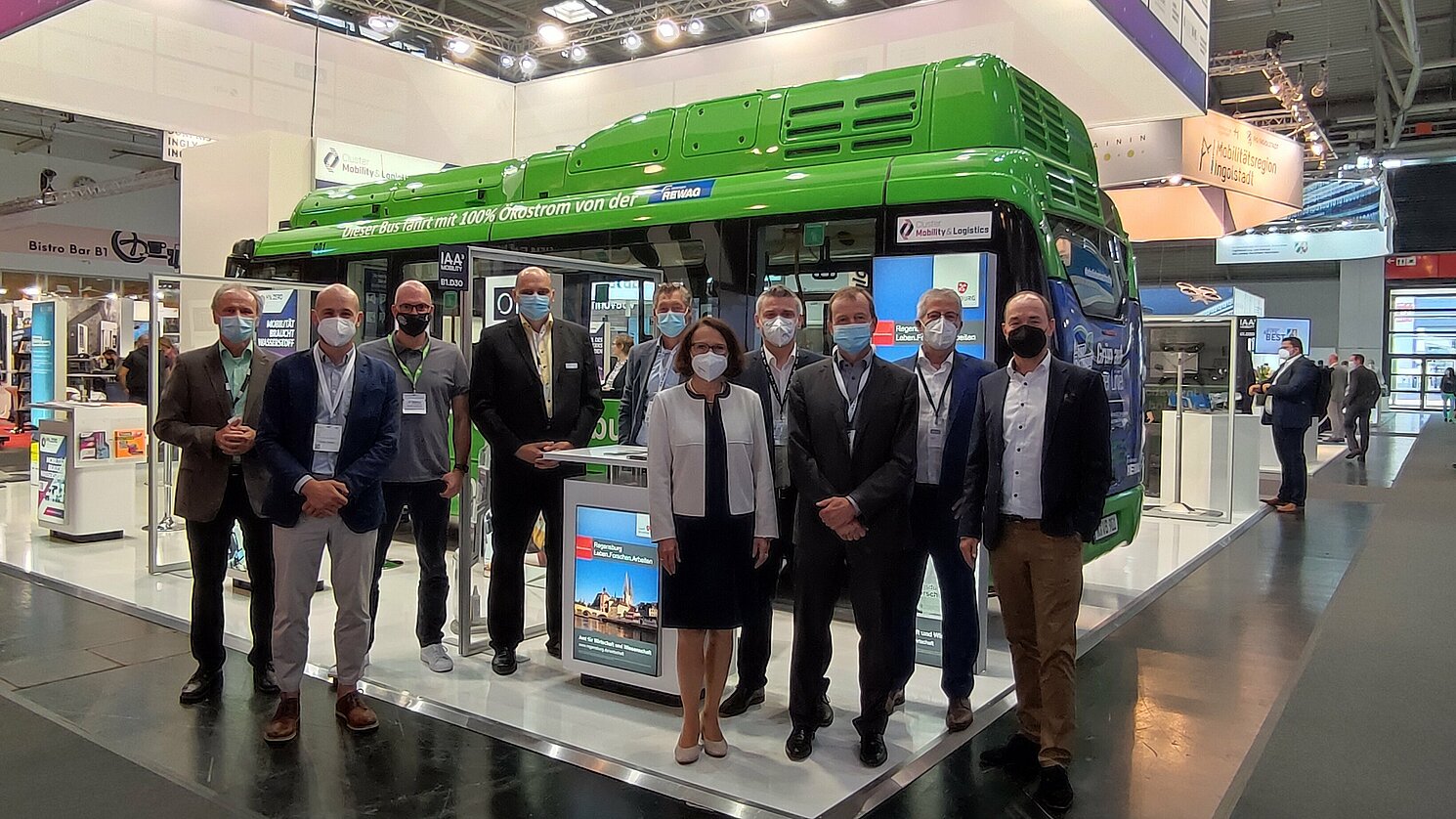 Gertrud Maltz-Schwarzfischer, Oberbürgermeisterin Stadt Regensburg, mit den Mitausstellern am Gemeinschaftsstand des Clusters Mobility & Logistics vor dem Elektro-Innovationsbus Emil.