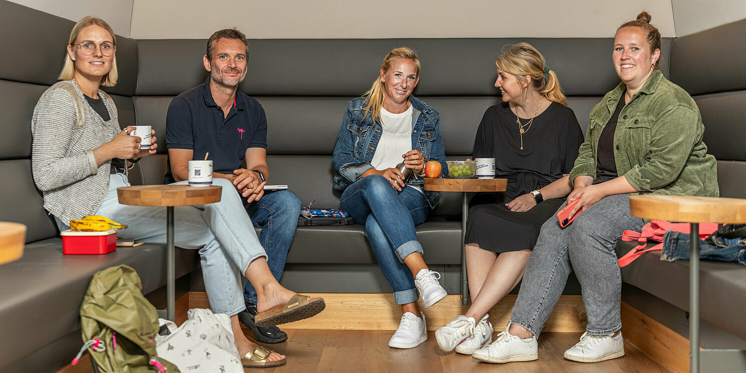 Studierende sitzen in der Cafeteria zusammen und unterhalten sich.