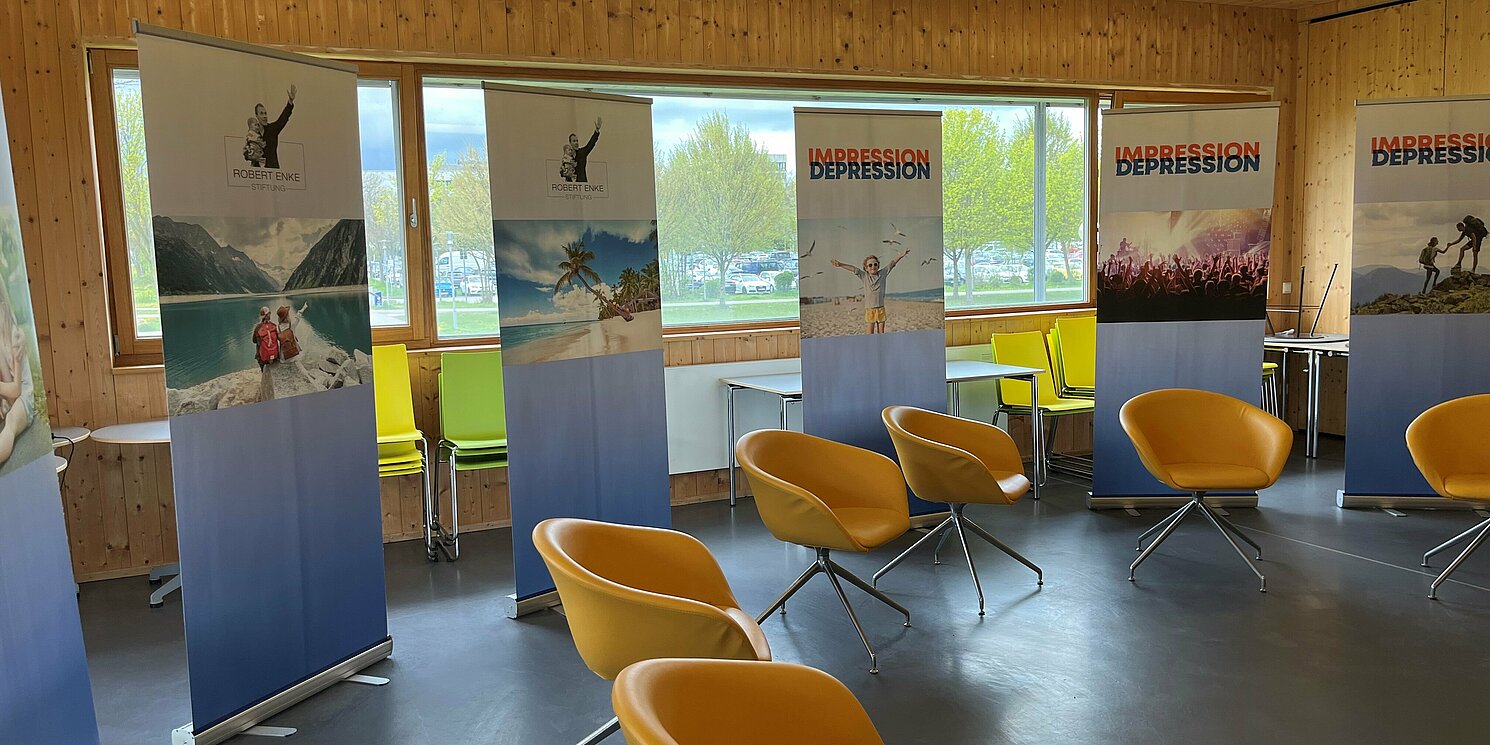 Impression_Depression Ein Raum im Studierendenhaus mit Stuhlkreis und Roll-Ups, die Natur und Menschen abbilden
