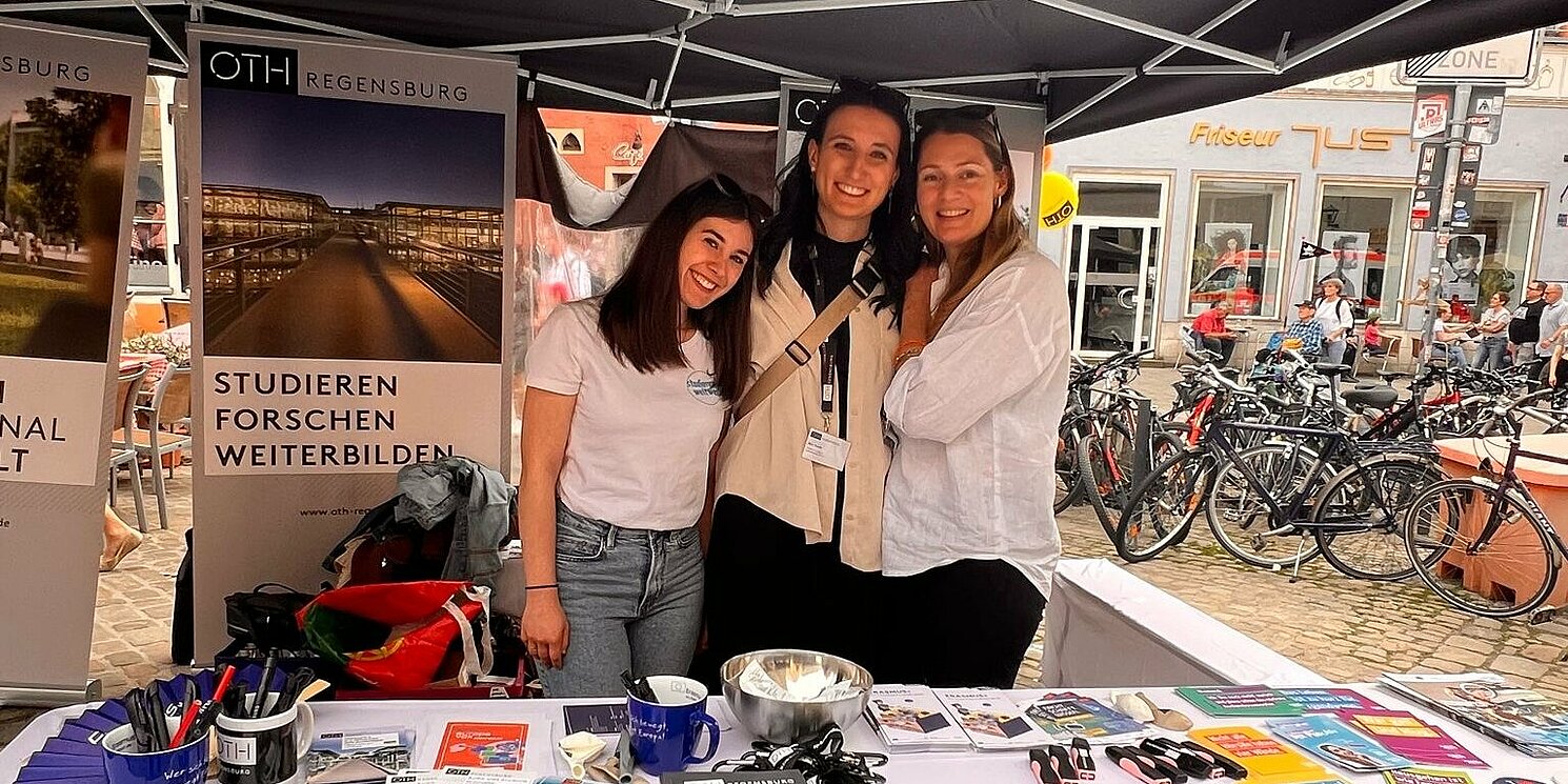 Drei Personen an einem Infostand.