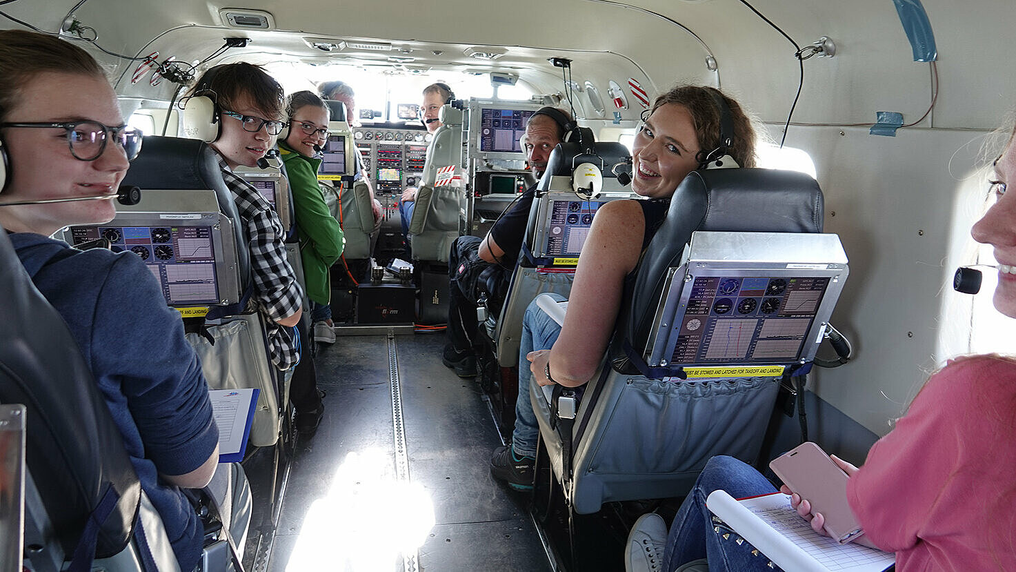 Maren Hupp (von links nach rechts), Sophia Säckl, Luise Gumberger, Marei Kuchler und Anna-Maria Günzinger mit Pilot, Copilot und Bordtechniker kurz vor dem Start Richtung Alpen.