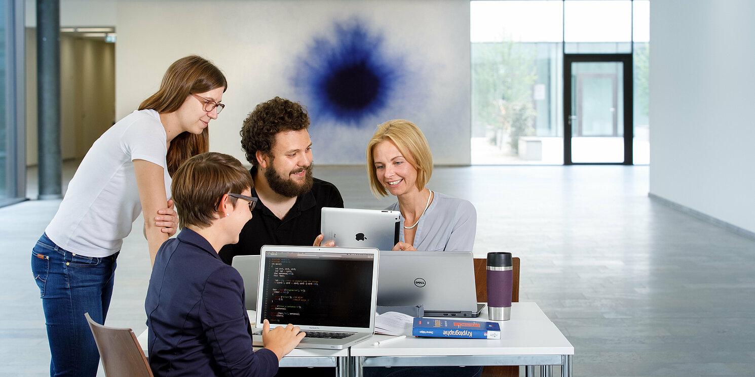 Vier Studierende sind in einer Lerngruppe mit Laptops und Büchern zusammen gekommen