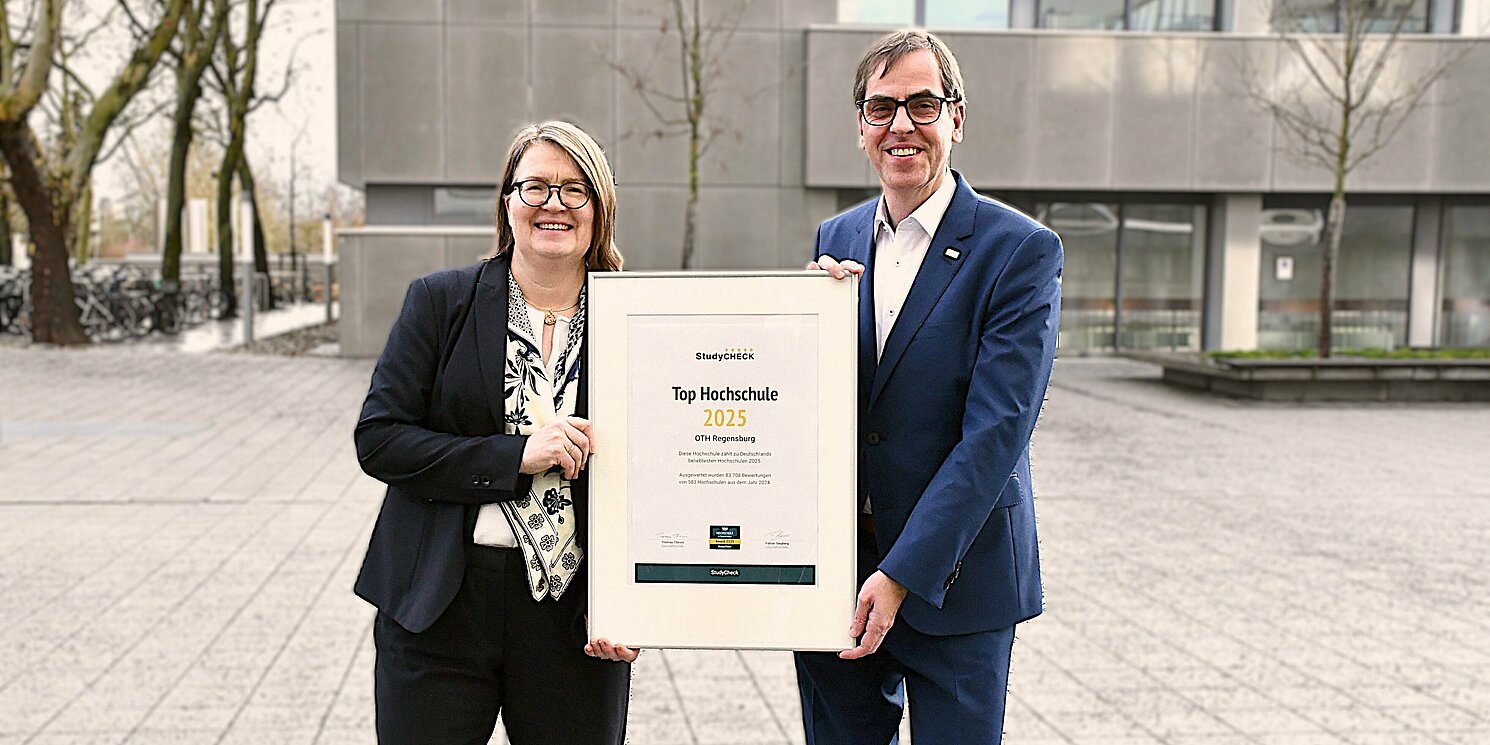 Zwei Personen halten eine gerahmte Urkunde