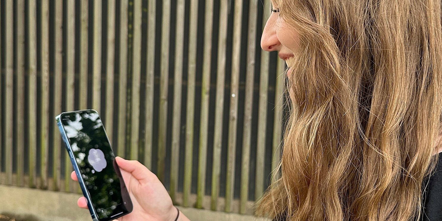 Eine junge Frau schaut auf ihr Smartphone.