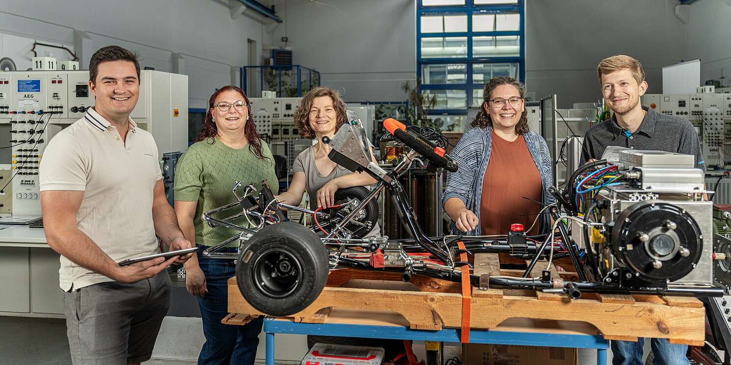 Fünf Studierende arbeiten an einem Fahrzeug. 