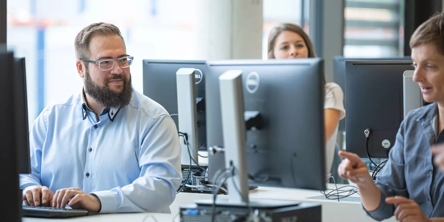Hochschulzertifikat Künstliche Intelligenz berufsbegleitend absolvieren Studierende arbeiten in einem Computerraum an ihren Rechnern.