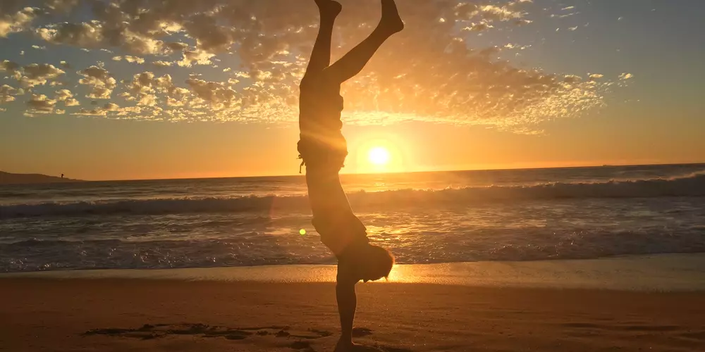 Studing doing a handstand at the beach during sunset