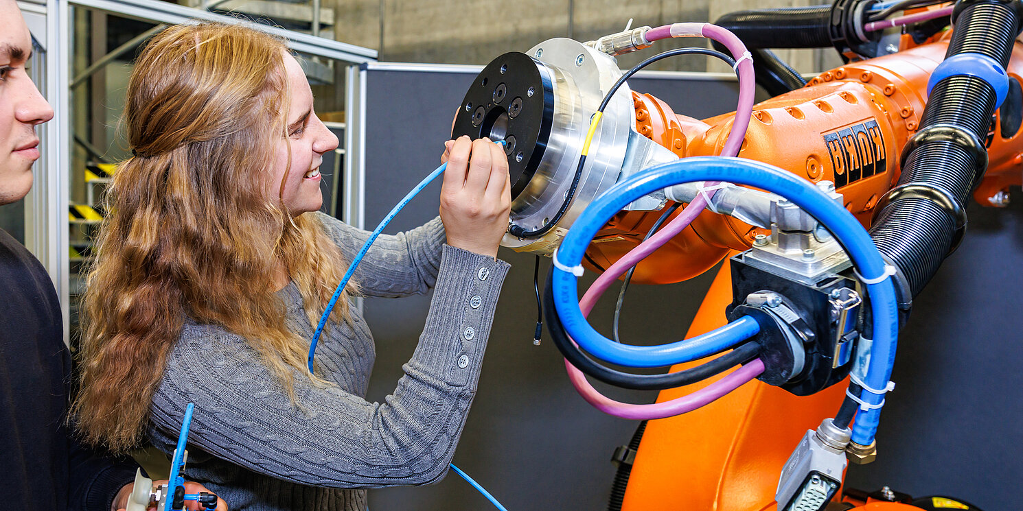 Zwei Studierende bei der Arbeit an einem Roboterarm im Labor Robotik