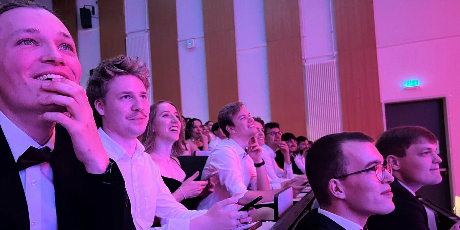 Zu sehen ist 1-2 Reihen im Hörsaal, gut gefüllt mit Dynamics-Mitglieder. Alle sind gut gelaunt, lachen, haben das Smartphone in der Hand, um an einem Kahoot-Quiz teilzunehmen. 