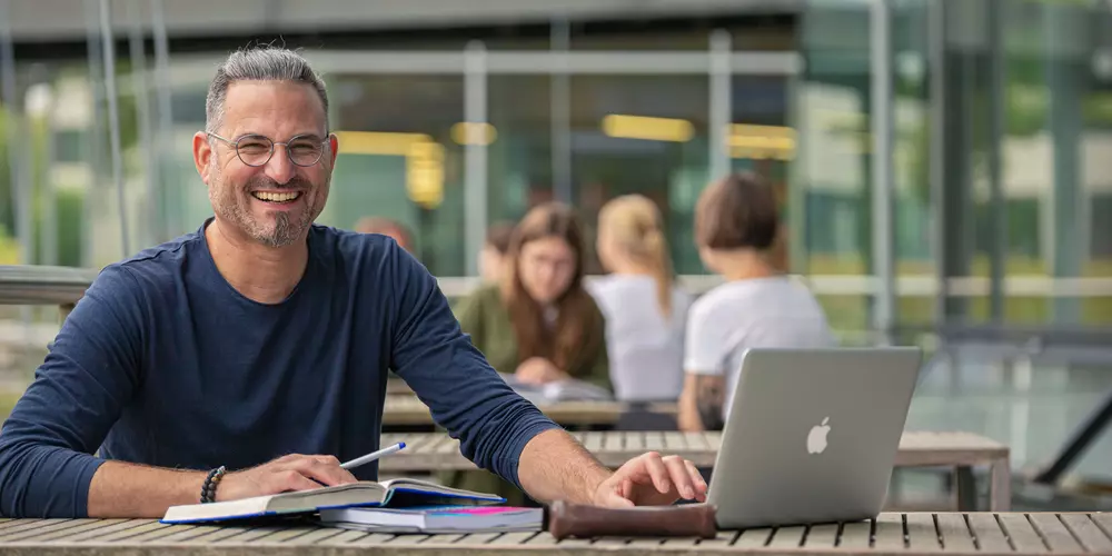Module aus unseren berufsbegleitenden Studiengängen  Studierende auf einem Steg über dem Mensa-See lernen an Arbeitsplätzen
