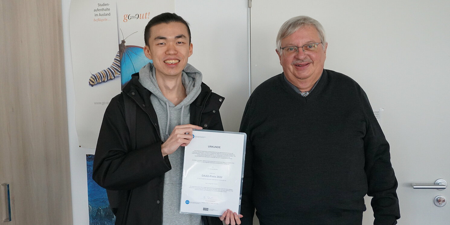 Für seine hervorragenden Leistungen wurde ihm der DAAD-Preis 2022 verliehen und von Dr. Wilhelm Bomke, Leiter des International Office, die Urkunde überreicht. Foto: OTH Regensburg/Claudia Trotzke