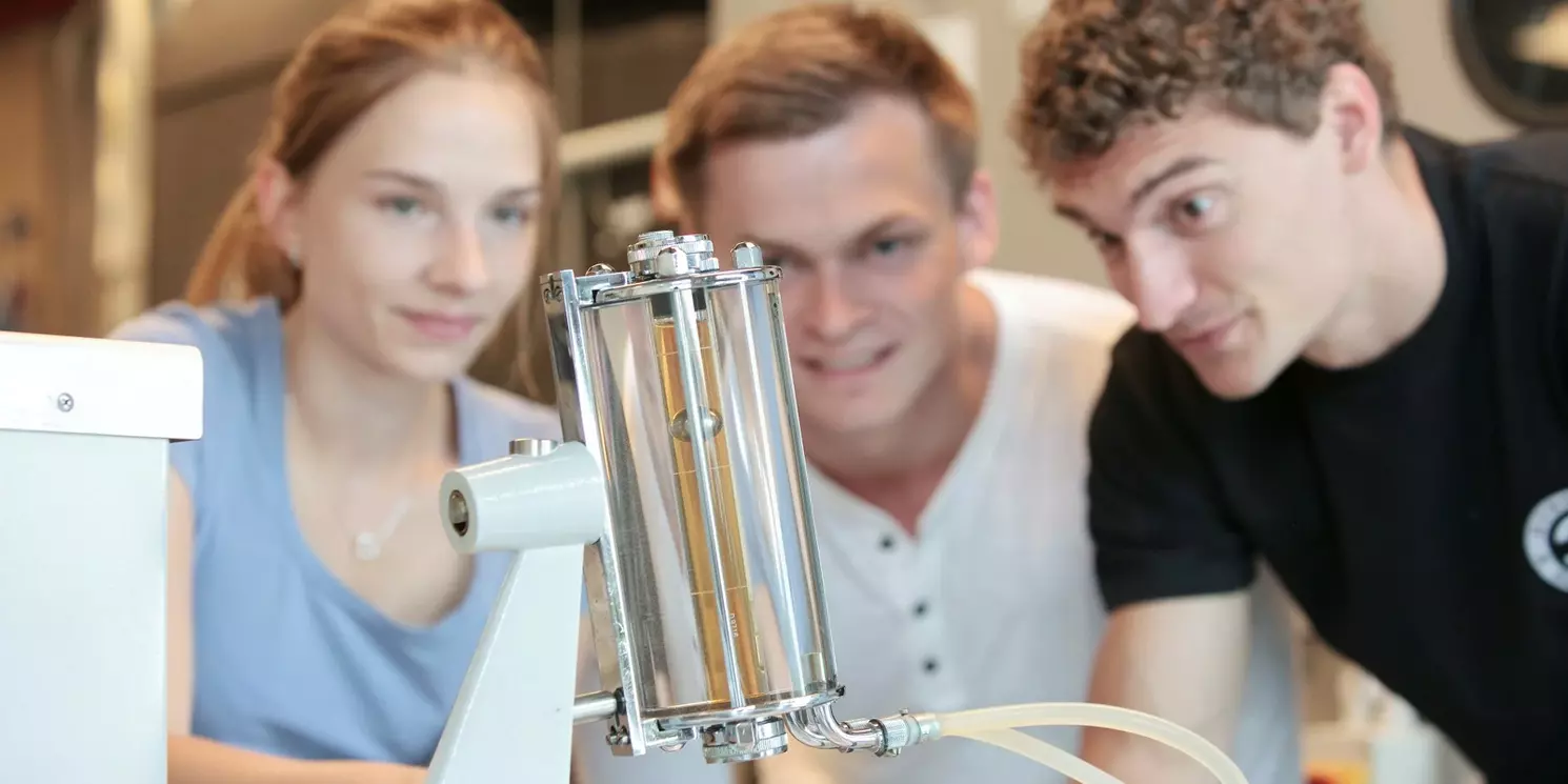 Studierende beobachten ein Demonstrationsmodell eines Stirlingmotors