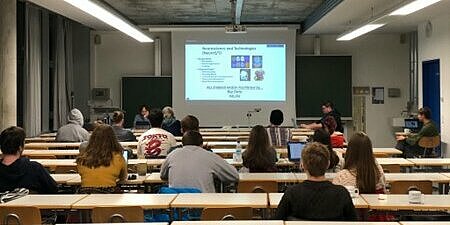 Ein Hörsaal in dem Studierende eine Power-Point-Präsentation betrachten.