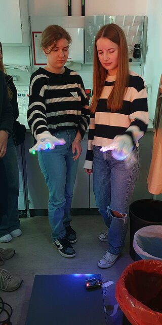 Zwei Mädchen mit Handschuh spielen Lichtharfe.