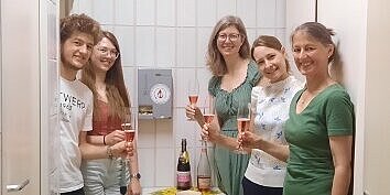 Fünf Personen stehen zuasmmen und haben je ein Glas in der Hand.