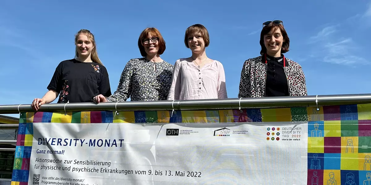 Elisabeth Hockemeyer, Andrea März-Bäuml, Karolin Kirowa, Johanna Ertl auf der Brücke am Campus mit dem Banner zum Diversity-Monat
