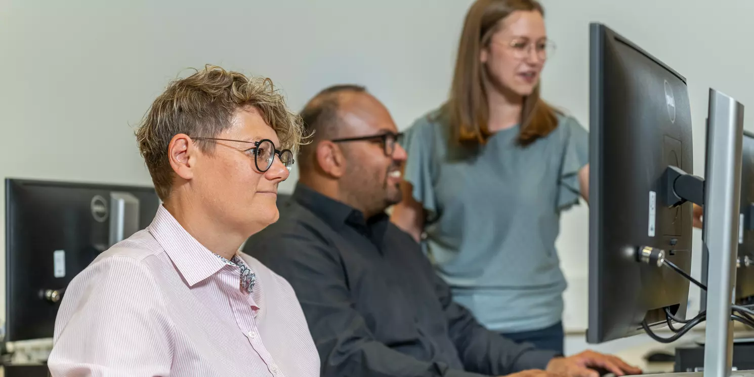 International Summer School: Trustworthy AI – Machine Learning Meets Blockchain Drei Studierende arbeiten in einem CIP-Pool an ihren Rechnern und unterhalten sich.