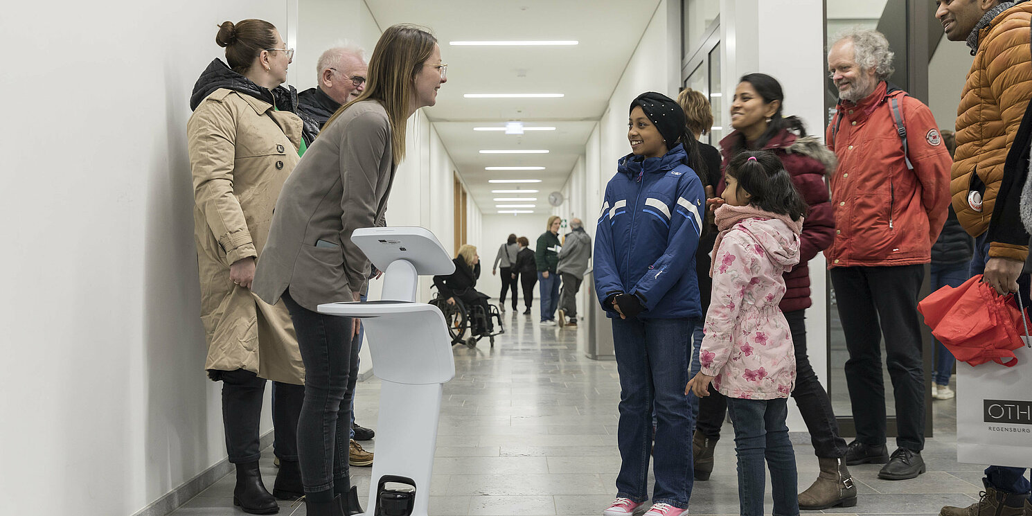 Kinder und Erwachsene stehen vor einem Roboter.