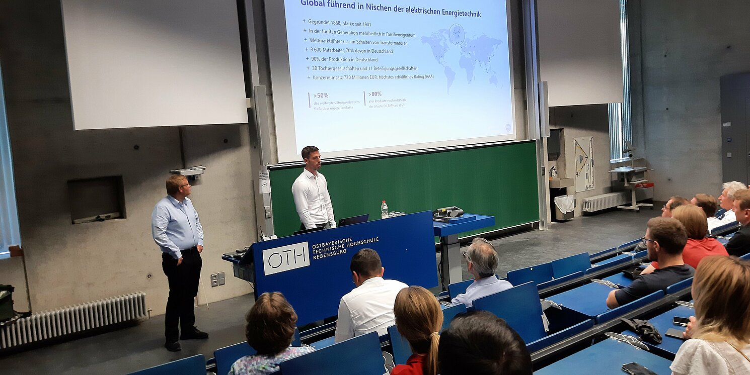 Moritz Bengler und Tobias Röhrl (Maschinenfabrik Reinhausen GmbH) zeigen auf, wie Künstliche Intelligenz die Stabilität unserer Stromnetze steigern kann. Foto: Katja Meier