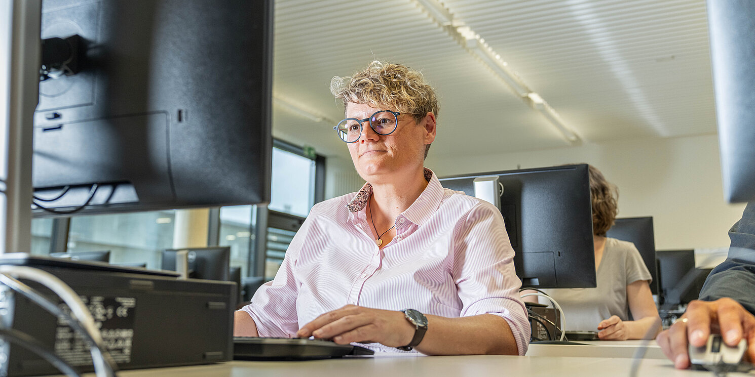 Study Car IT and Electronics part-time Studentin sitzt vor einem PC und arbeitet in einem Kursraum